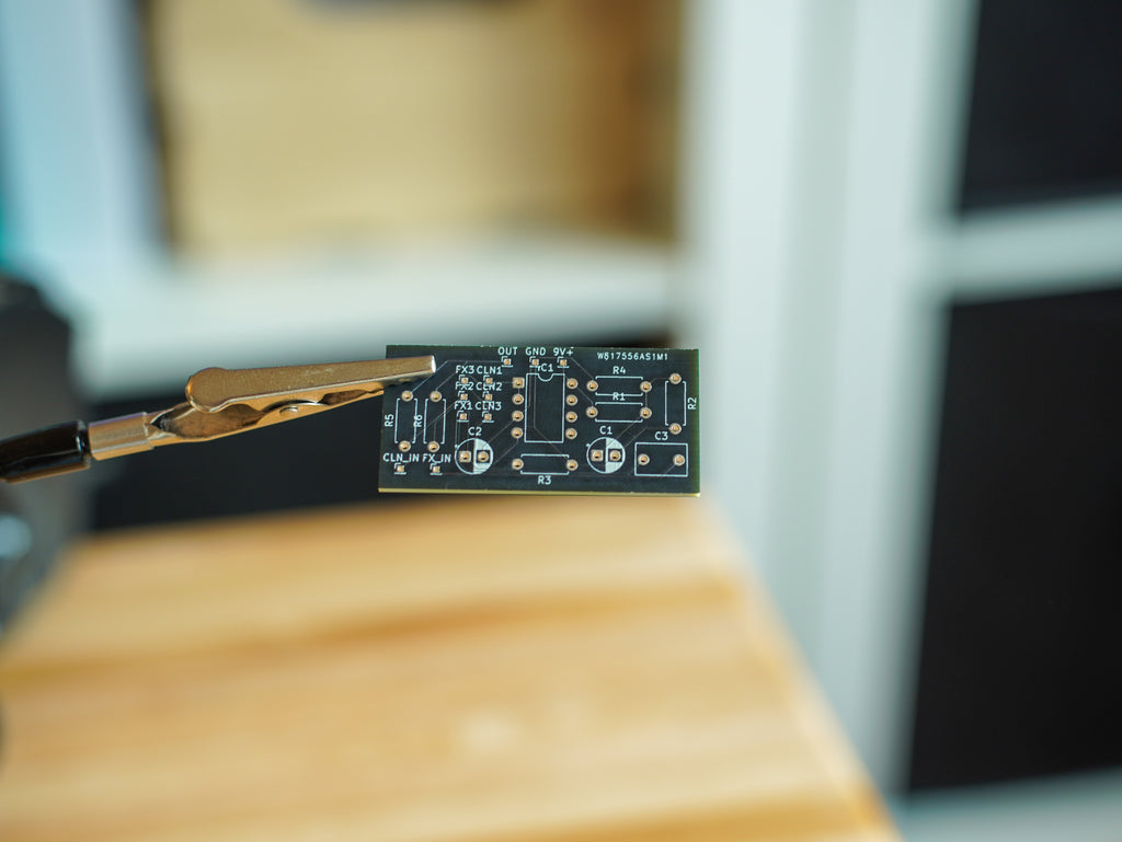 Close-up of a small electronic component on a wooden surface with a blurred background