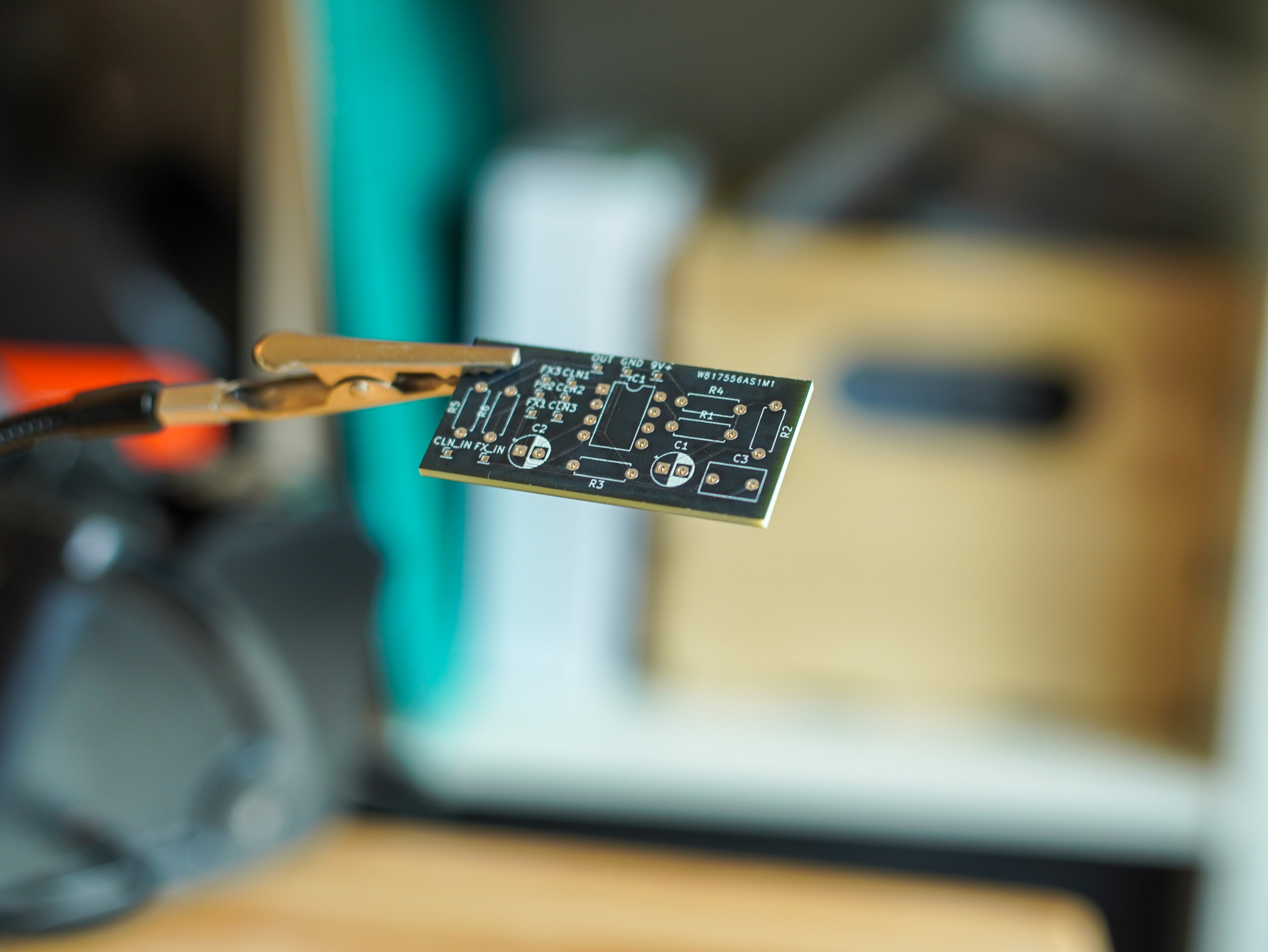 Close-up of a circuit board held by tweezers with a blurred background