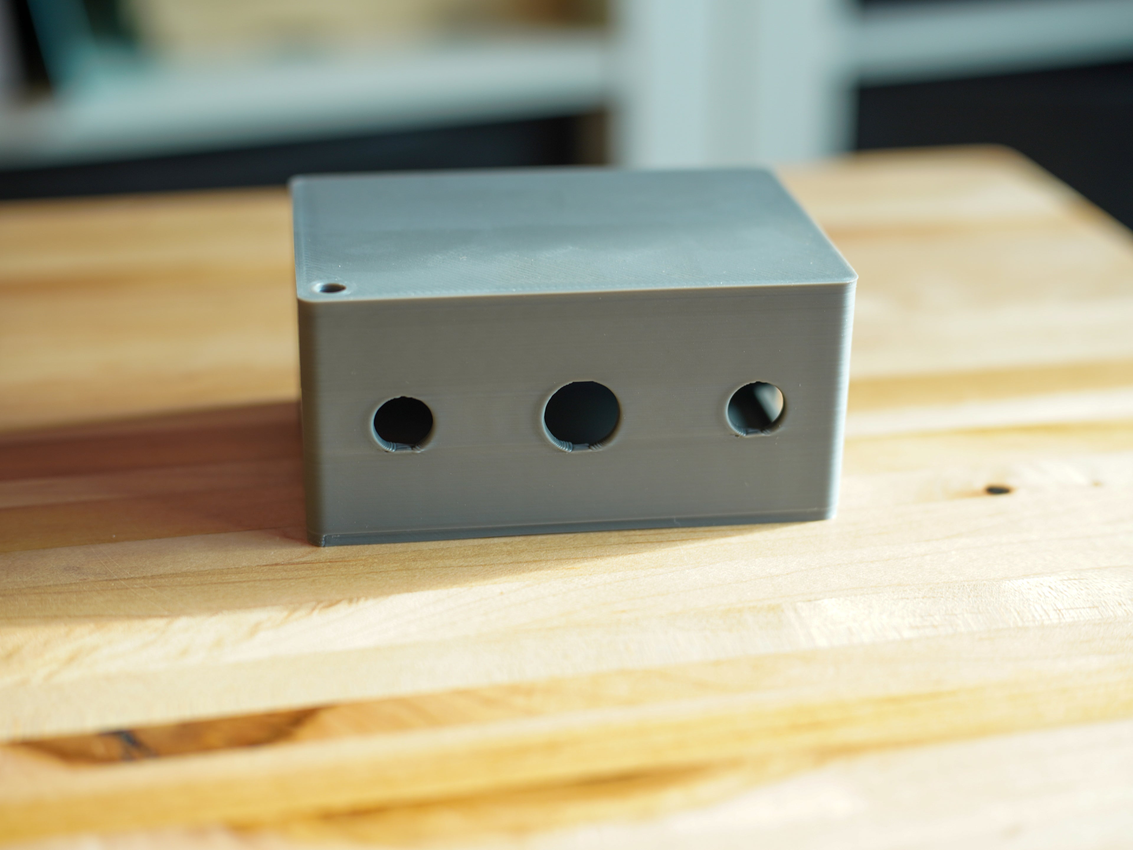 Plastic box with three holes on a wooden surface